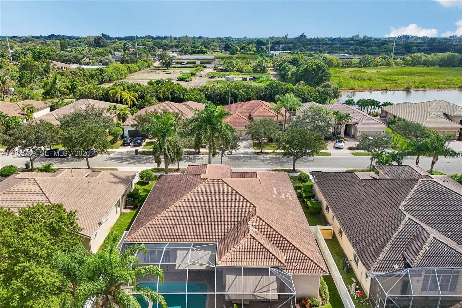 6353 SW 191st Avenue, Pembroke Pines, FL 33332 Aerial perspective featuring a tile roof, an enclosed swimming pool, mature palm trees, and native vegetation