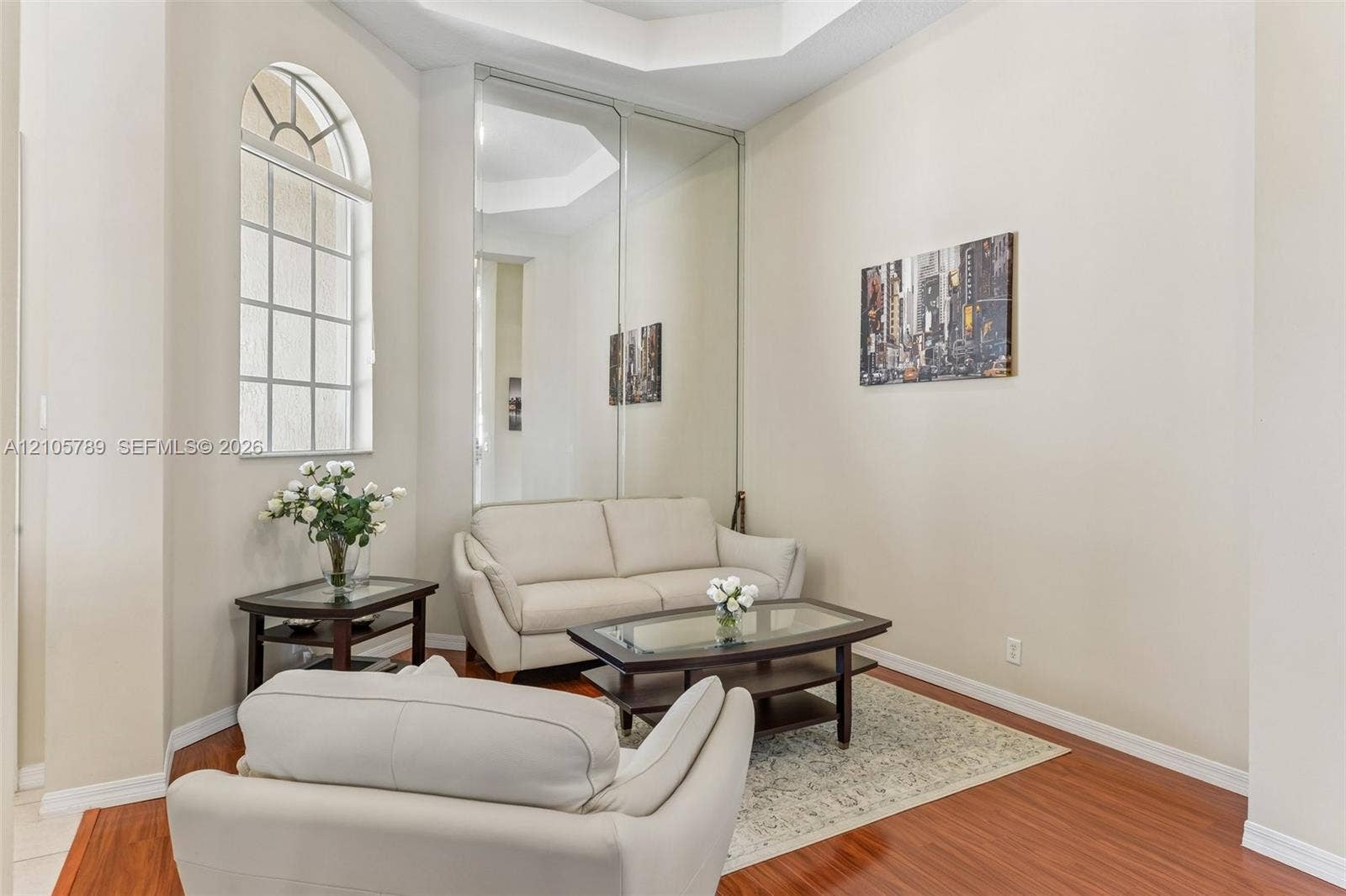 6353 SW 191st Avenue, Pembroke Pines, FL 33332 Room featuring high ceilings, wood-finish flooring, an arched window, and floor-to-ceiling mirrored panels