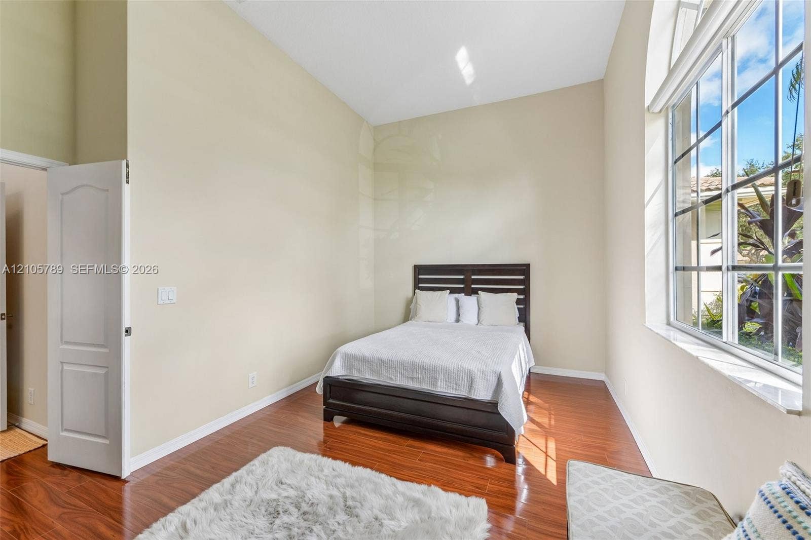 6353 SW 191st Avenue, Pembroke Pines, FL 33332 High vaulted ceilings featuring a large arched window with natural light, paired with dark-toned wood-finish flooring and a multi-panel interior door