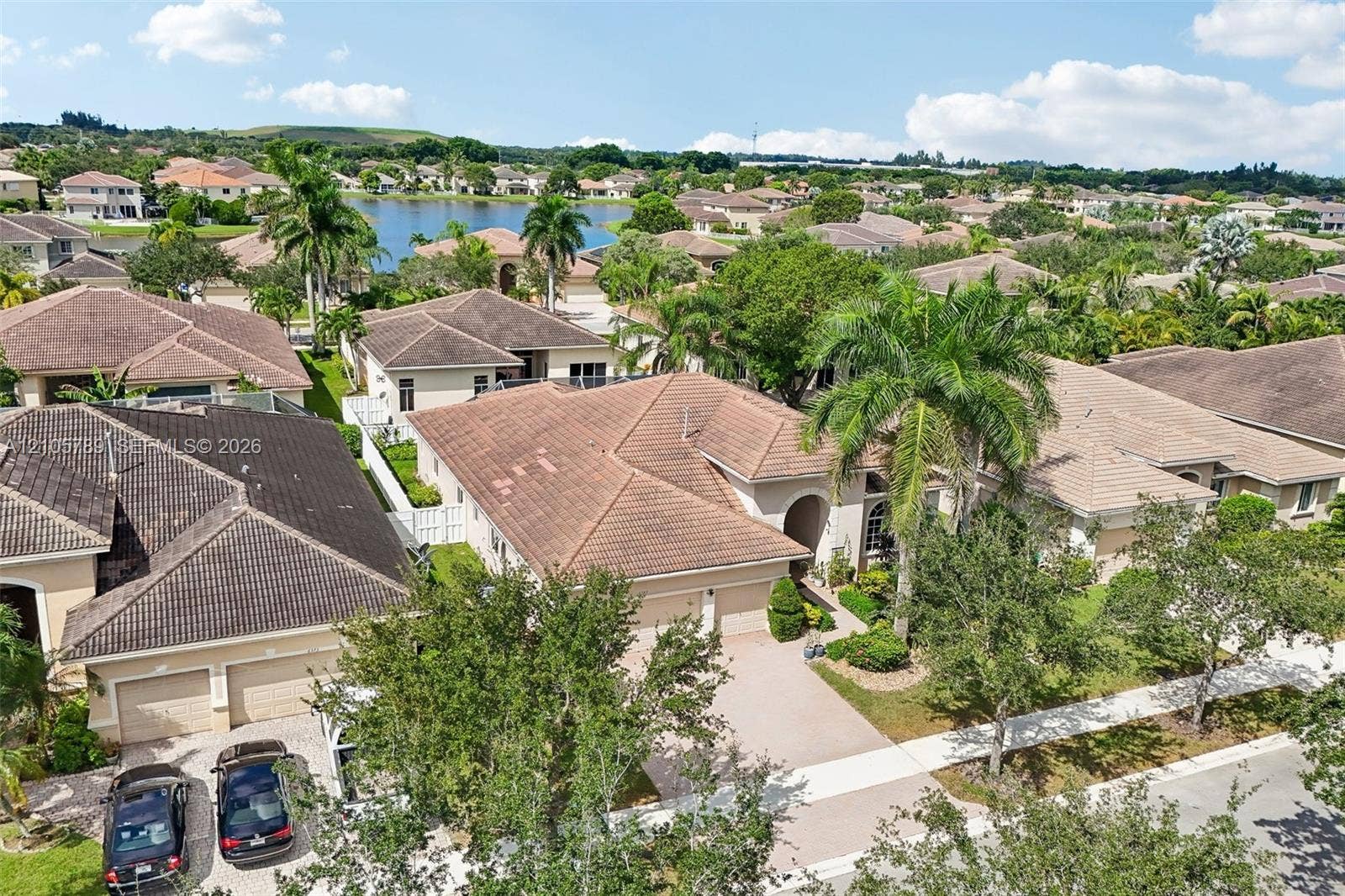 6353 SW 191st Avenue, Pembroke Pines, FL 33332 Aerial perspective of a single-story residence featuring a multi-pitched tile roof, concrete paver driveway, two-car garage, and mature palm landscaping