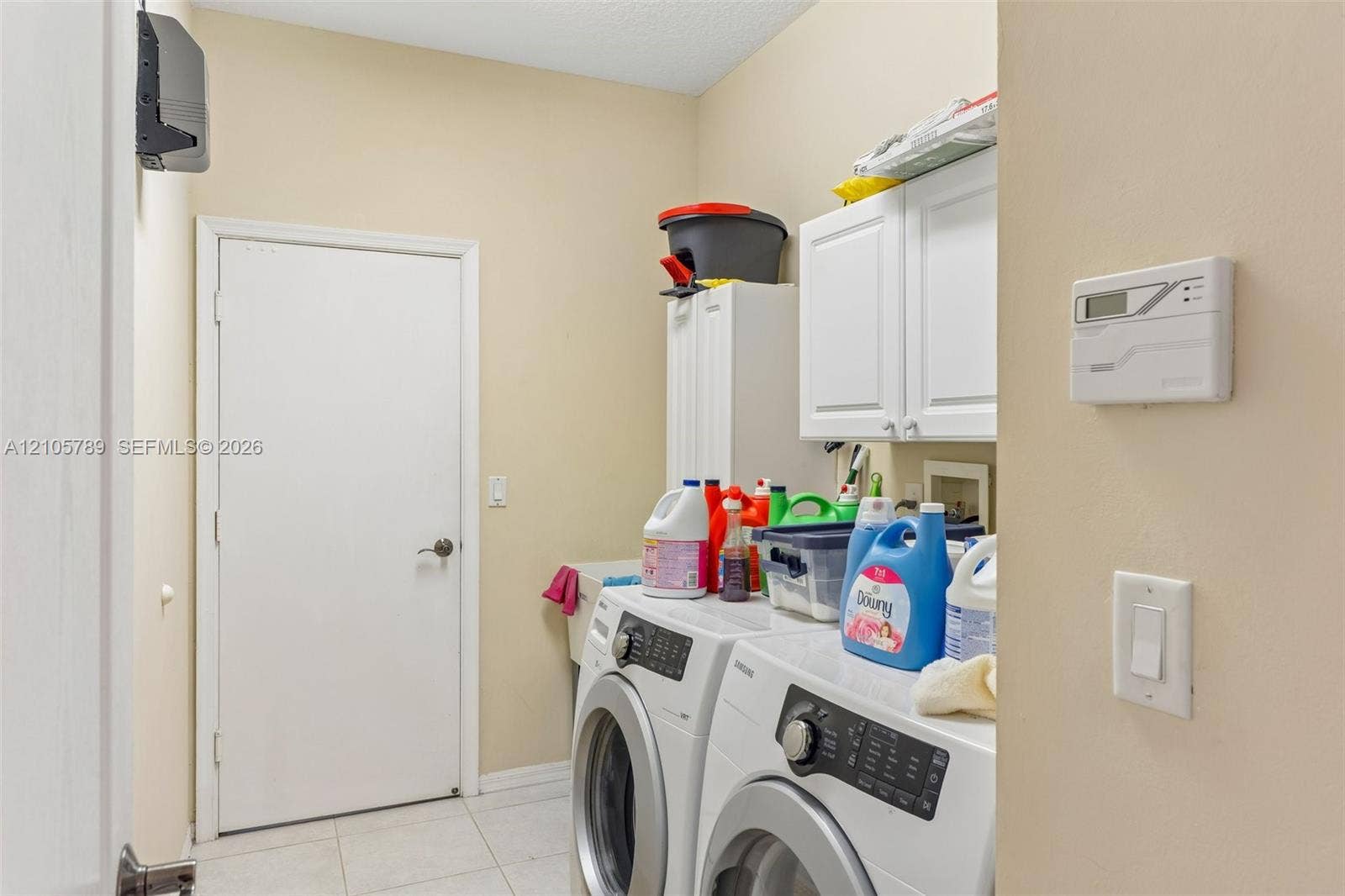 6353 SW 191st Avenue, Pembroke Pines, FL 33332 Laundry room featuring white wall-mounted cabinetry, tile flooring, and a built-in utility sink