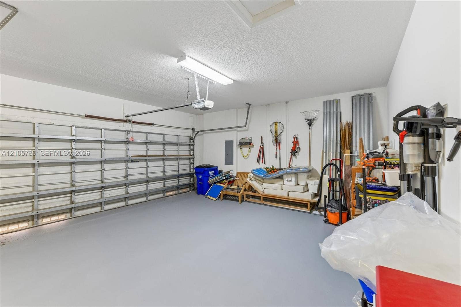 6353 SW 191st Avenue, Pembroke Pines, FL 33332 Enclosed garage featuring a metal overhead door, finished flooring, an integrated ceiling light fixture, and an automated door opener