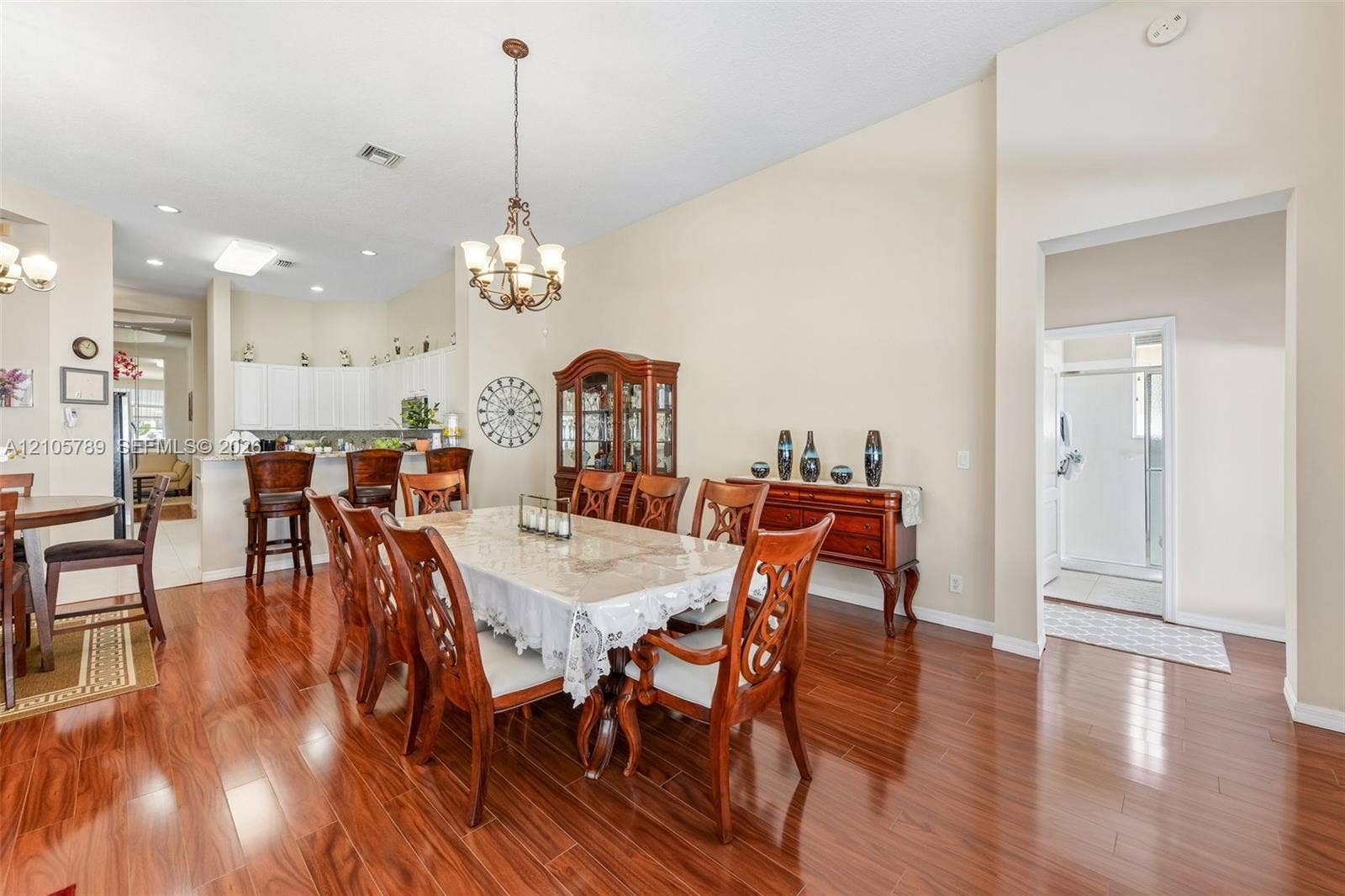 6353 SW 191st Avenue, Pembroke Pines, FL 33332 Open-concept floor plan featuring high ceilings, wood-finish flooring, a multi-tiered breakfast bar, and a decorative chandelier