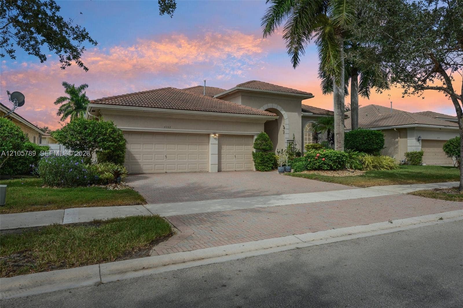 6353 SW 191st Avenue, Pembroke Pines, FL 33332 Stucco exterior with a tiled roof, arched entryway, and two-car garage featuring paver driveway and mature landscaping