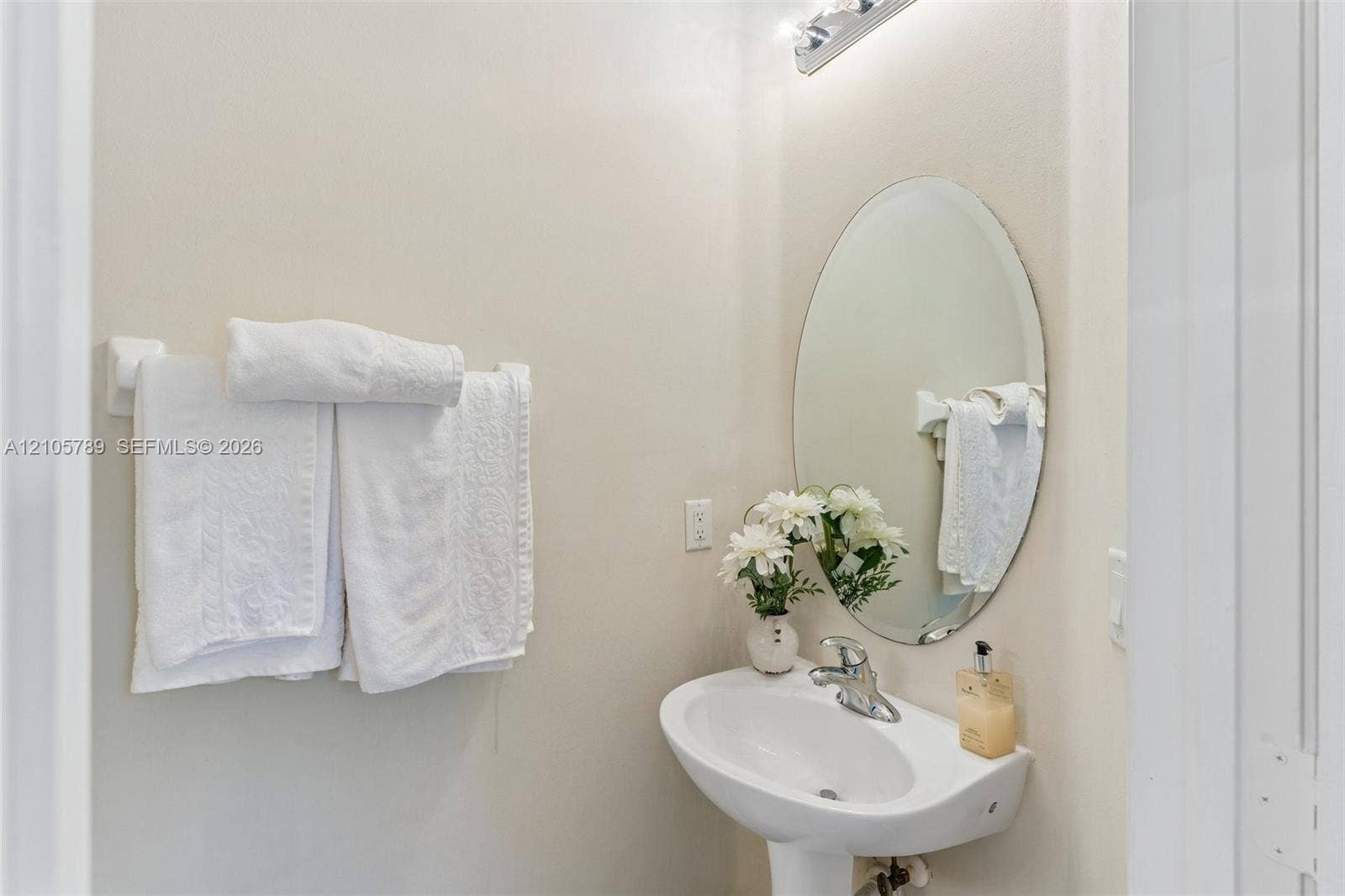 6353 SW 191st Avenue, Pembroke Pines, FL 33332 Oval wall-mounted mirror, white pedestal sink, chrome faucet fixture, and multi-bulb vanity lighting