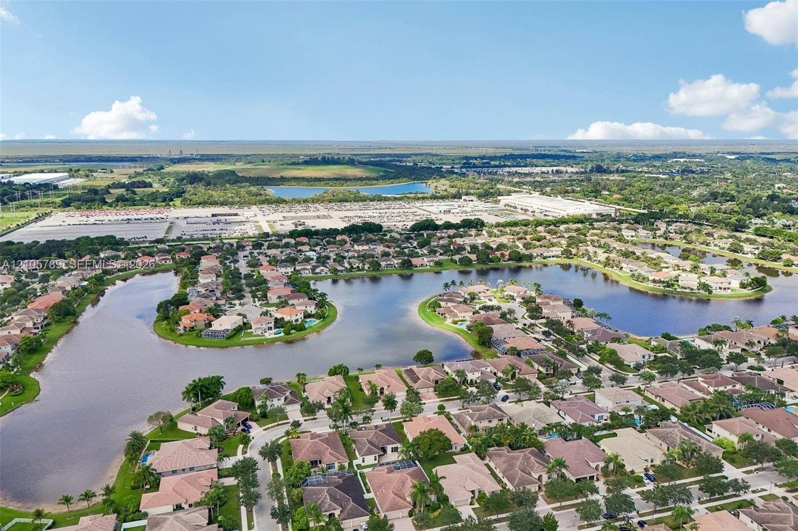 6353 SW 191st Avenue, Pembroke Pines, FL 33332 Aerial perspective of a residential community featuring extensive waterfront acreage, winding roadways, uniform tile roofing, and mature perimeter landscaping