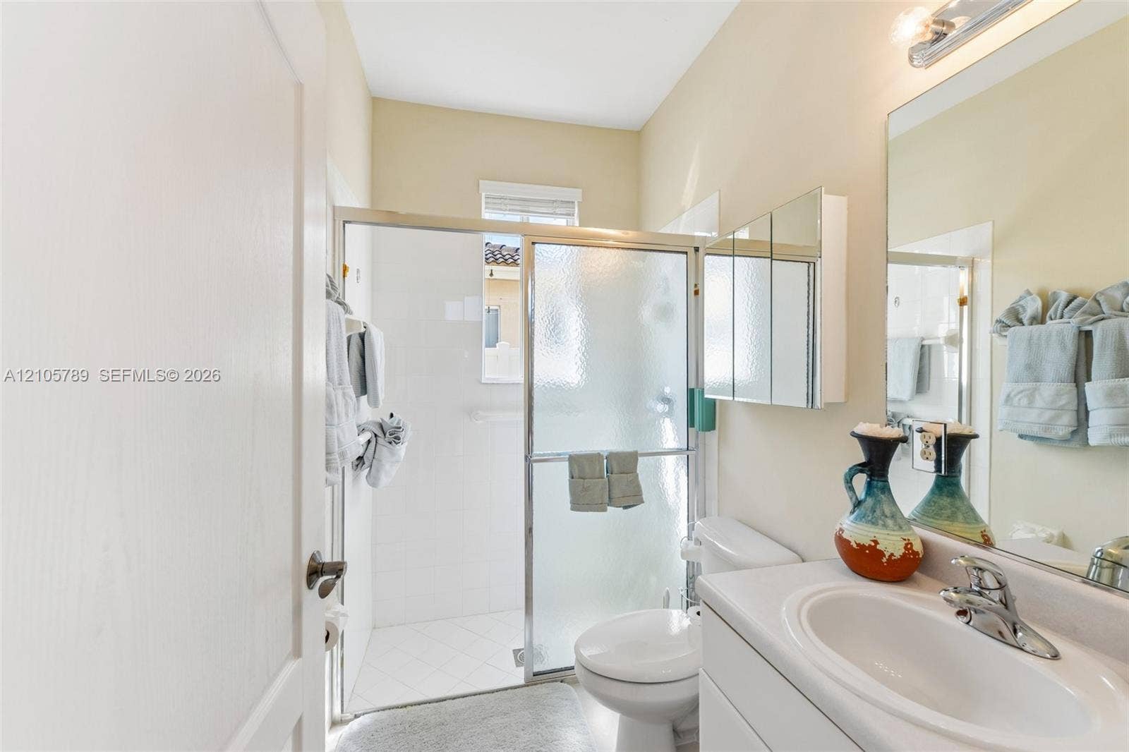 6353 SW 191st Avenue, Pembroke Pines, FL 33332 Bathroom featuring a glass-enclosed shower, white vanity with an integrated sink, polished chrome faucet, and tri-fold mirrored medicine cabinet