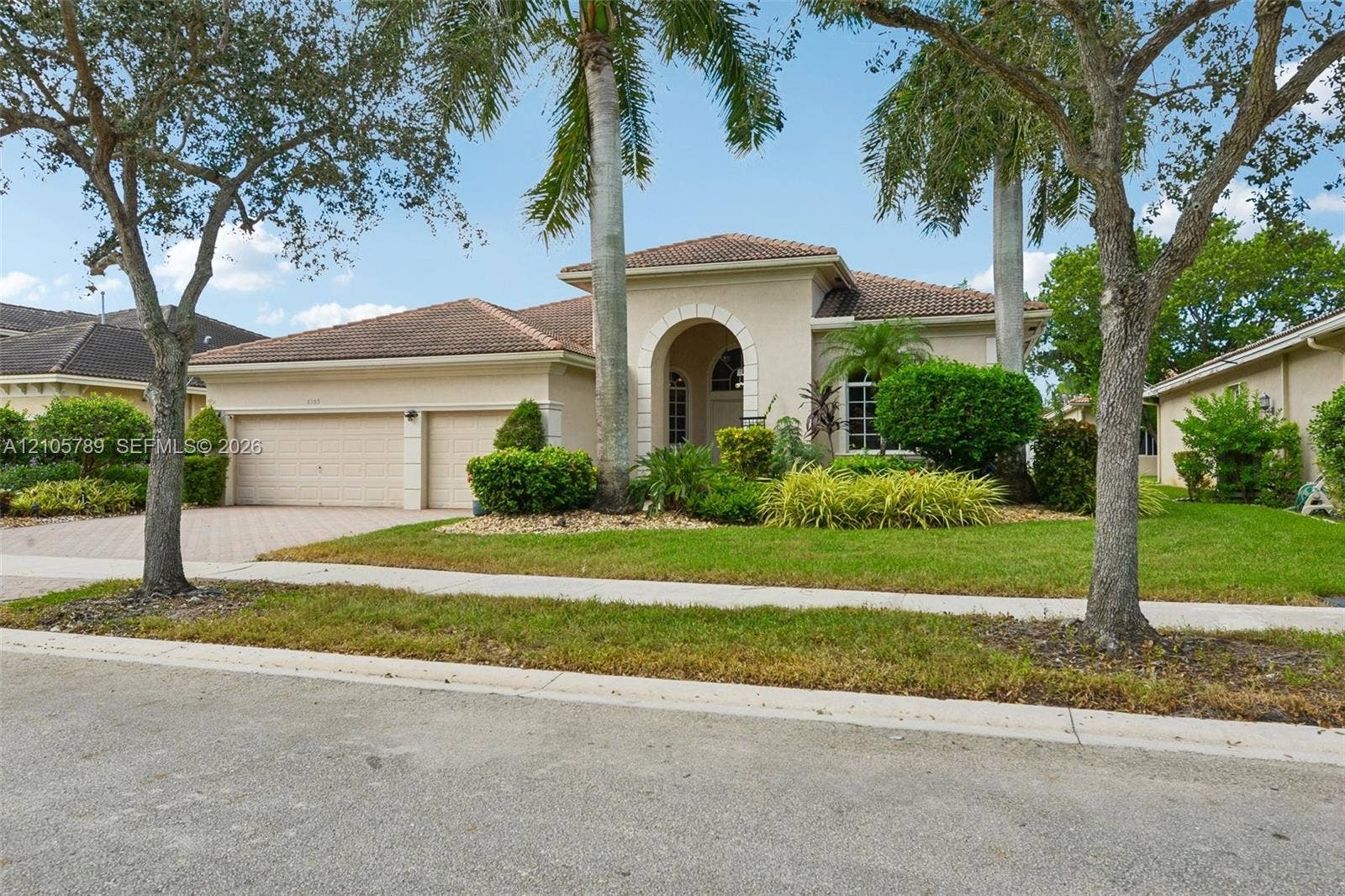 6353 SW 191st Avenue, Pembroke Pines, FL 33332 Stucco exterior featuring an arched entryway, a tile roof, a three-car garage, and a brick-paver driveway