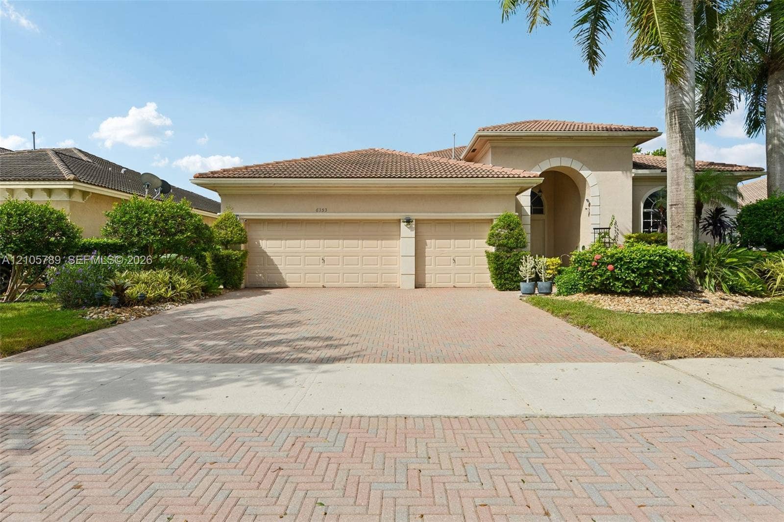 6353 SW 191st Avenue, Pembroke Pines, FL 33332 Stucco exterior with a tiled roof, arched entryway, two-car garage, and herringbone-patterned paved driveway