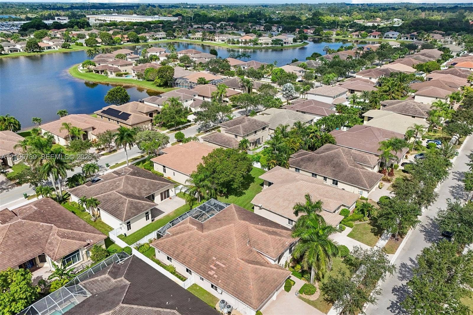 6353 SW 191st Avenue, Pembroke Pines, FL 33332 Aerial perspective featuring a residential community with tiled-roof structures, screen-enclosed pool enclosures, established landscaping, and a central lake