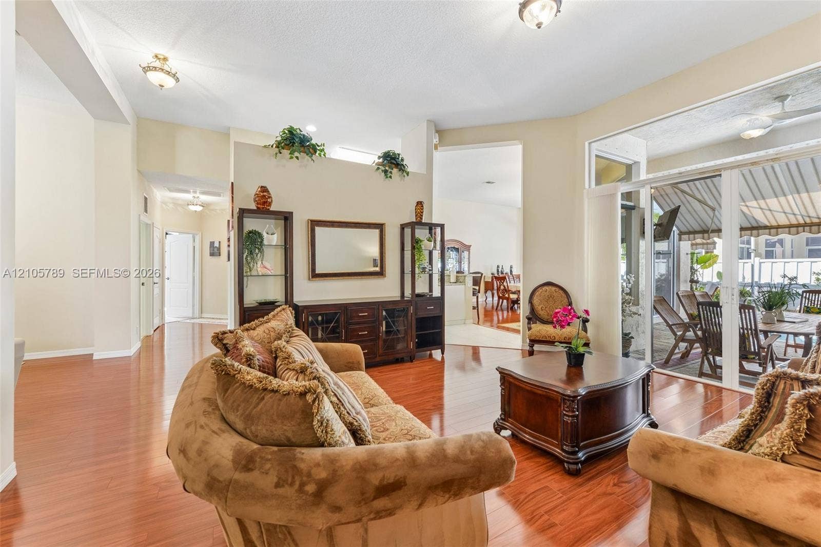 6353 SW 191st Avenue, Pembroke Pines, FL 33332 Living area featuring wood-finish flooring, vaulted ceilings, recessed lighting, and large glass sliding doors providing entry to a covered outdoor patio