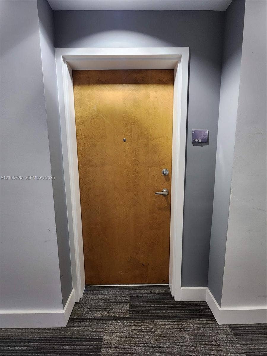 300 S Australian Avenue, #426, West Palm Beach, West Palm Beach, FL 33401 Solid-core wood-finish door with brushed metallic hardware, integrated security peephole, and white architectural casing