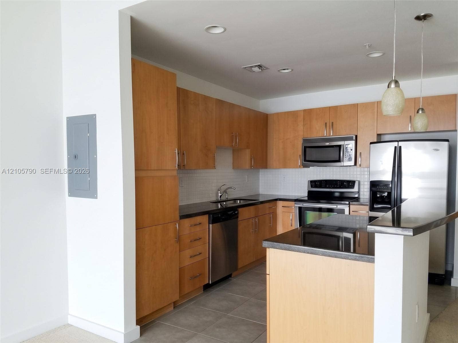 300 S Australian Avenue, #426, West Palm Beach, West Palm Beach, FL 33401 Kitchen featuring natural wood cabinetry, dark stone countertops, stainless steel appliances, tile backsplash, and two pendant lights