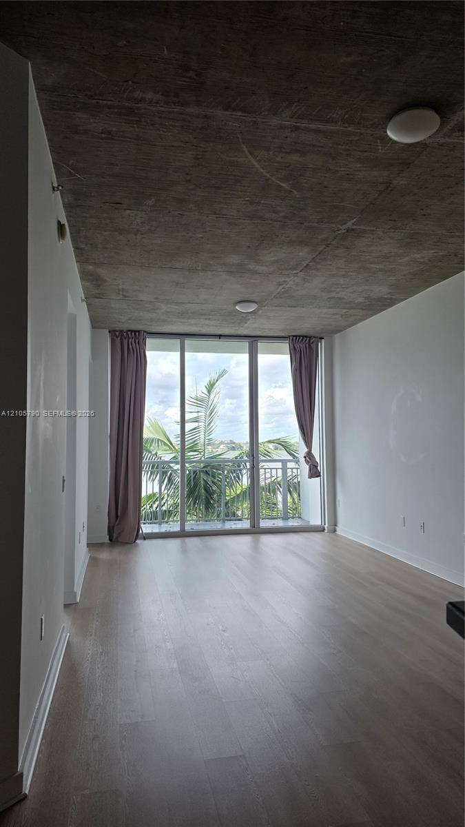 300 S Australian Avenue, #426, West Palm Beach, West Palm Beach, FL 33401 Floor-to-ceiling windows, industrial-style exposed concrete ceiling, light-toned wood-finish flooring, and balcony access