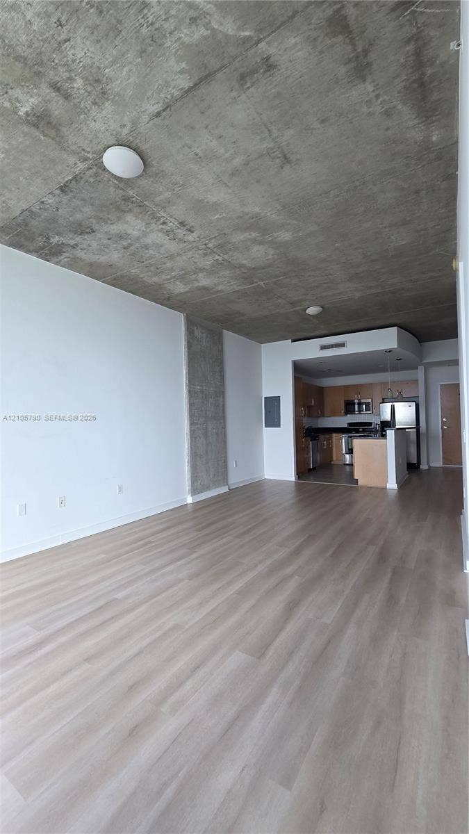 300 S Australian Avenue, #426, West Palm Beach, West Palm Beach, FL 33401 Exposed concrete ceiling, wood-finish flooring, and open-concept layout featuring a kitchen with stainless steel appliances and cabinetry
