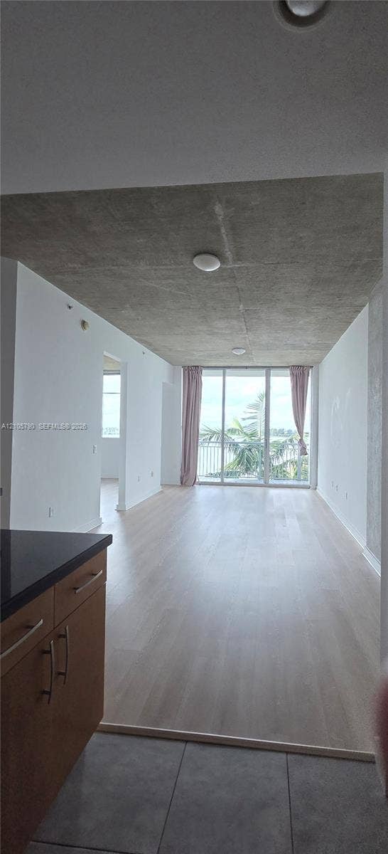 300 S Australian Avenue, #426, West Palm Beach, West Palm Beach, FL 33401 Exposed concrete ceiling, floor-to-ceiling glass doors, wood-finish flooring, and kitchen cabinetry featuring dark stone countertops