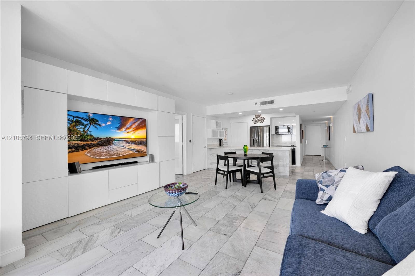 1830 S Ocean Drive, #4210, Hallandale Beach, Hallandale Beach, FL 33009 Living area featuring large-format stone tile flooring, custom white built-in media cabinetry, and an open kitchen with stone-topped island and white cabinetry