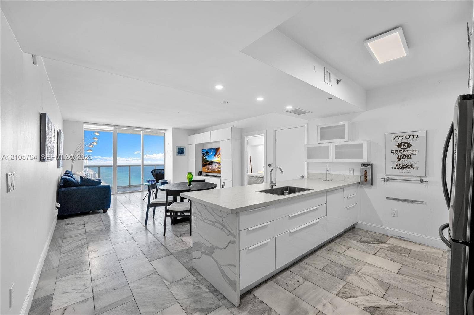 1830 S Ocean Drive, #4210, Hallandale Beach, Hallandale Beach, FL 33009 Open-concept interior featuring stone flooring, kitchen island with stone waterfall countertop, built-in cabinetry, recessed lighting, and floor-to-ceiling glass panel windows