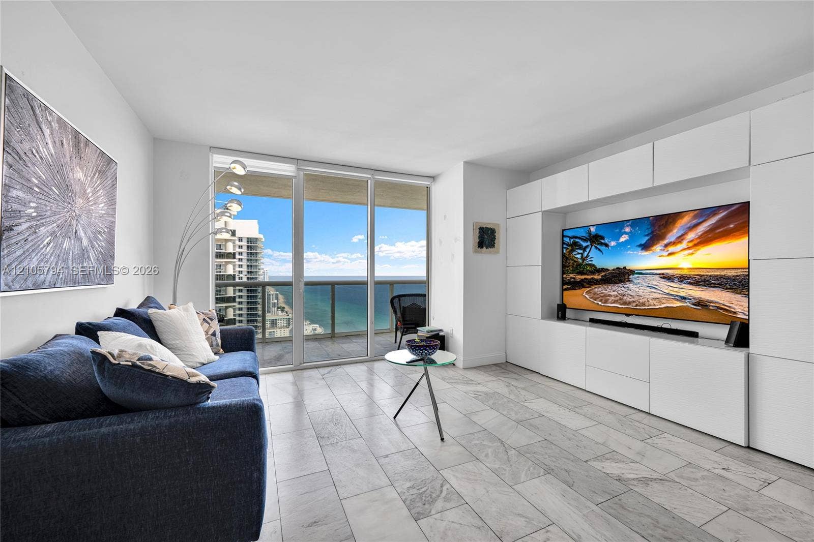 1830 S Ocean Drive, #4210, Hallandale Beach, Hallandale Beach, FL 33009 Living area featuring large-format tile flooring, floor-to-ceiling glass doors, and a custom built-in white cabinetry wall unit
