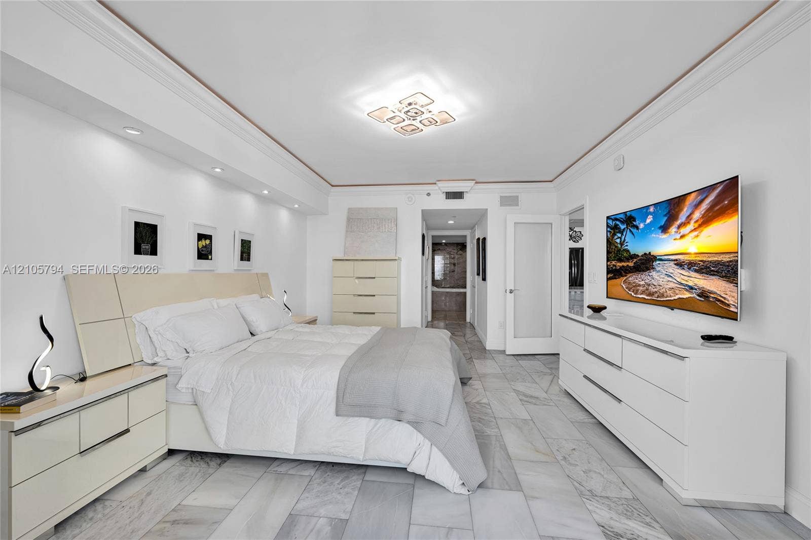 1830 S Ocean Drive, #4210, Hallandale Beach, Hallandale Beach, FL 33009 Neutral-toned interior featuring large-format stone-finish floor tile, recessed ceiling lighting, crown molding, and a dedicated wall-mounted lighting feature above the headboard area