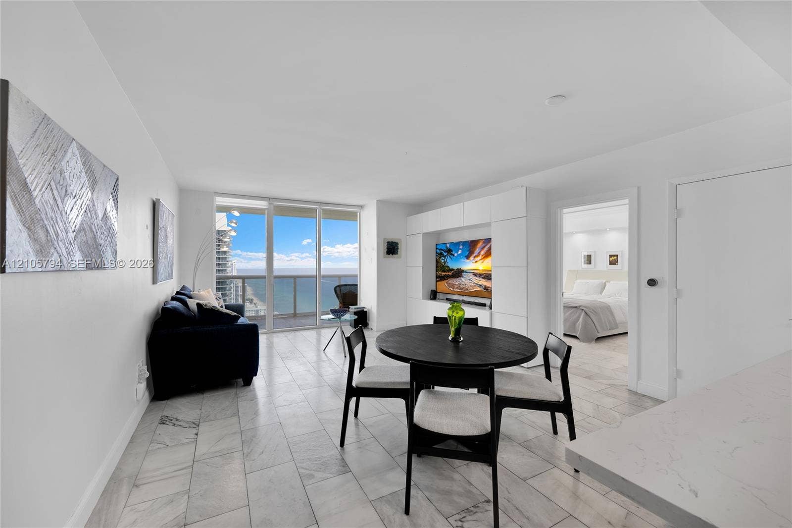 1830 S Ocean Drive, #4210, Hallandale Beach, Hallandale Beach, FL 33009 Floor-to-ceiling glass sliding doors, stone-finish tile flooring, built-in white wall cabinetry, and ocean backdrop