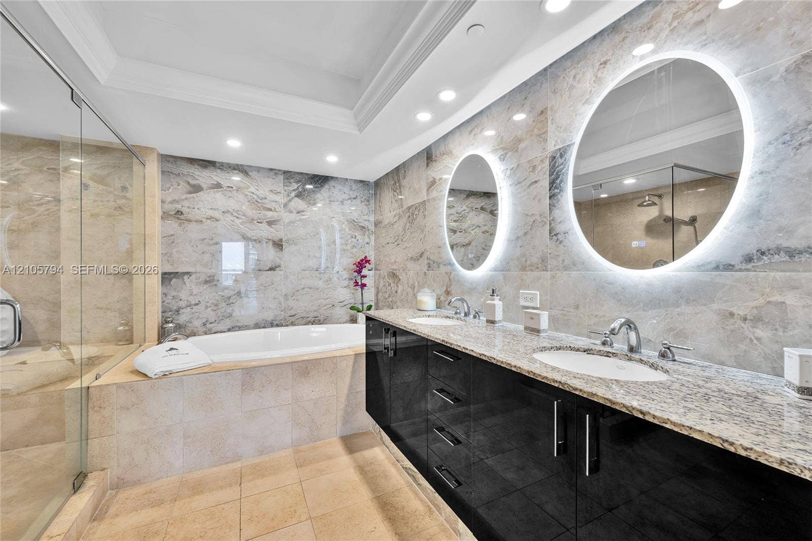 1830 S Ocean Drive, #4210, Hallandale Beach, Hallandale Beach, FL 33009 Double vanity with high-gloss cabinetry and stone countertops, oval LED-backlit mirrors, soaking tub with tile surround, and walk-in glass-enclosed shower