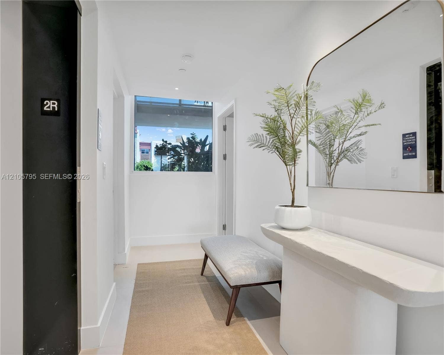 407 N Riverside Drive, #202, Pompano Beach, Pompano Beach, FL 33062 Entryway featuring a matte black elevator door, a built-in stone-finish console table, and a large wall-mounted mirror