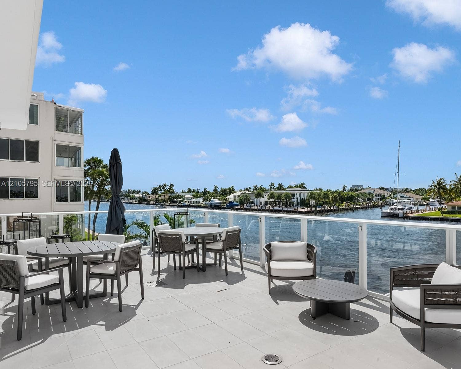 407 N Riverside Drive, #202, Pompano Beach, Pompano Beach, FL 33062 Expansive waterfront balcony featuring large-format stone tile flooring and a glass-paneled railing overlooking the canal