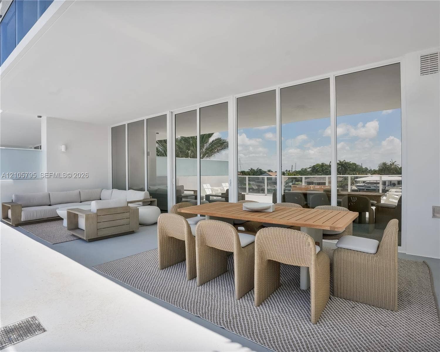 407 N Riverside Drive, #202, Pompano Beach, Pompano Beach, FL 33062 Expansive covered terrace featuring floor-to-ceiling glass wall panels, smooth concrete flooring, and an attached white railing system