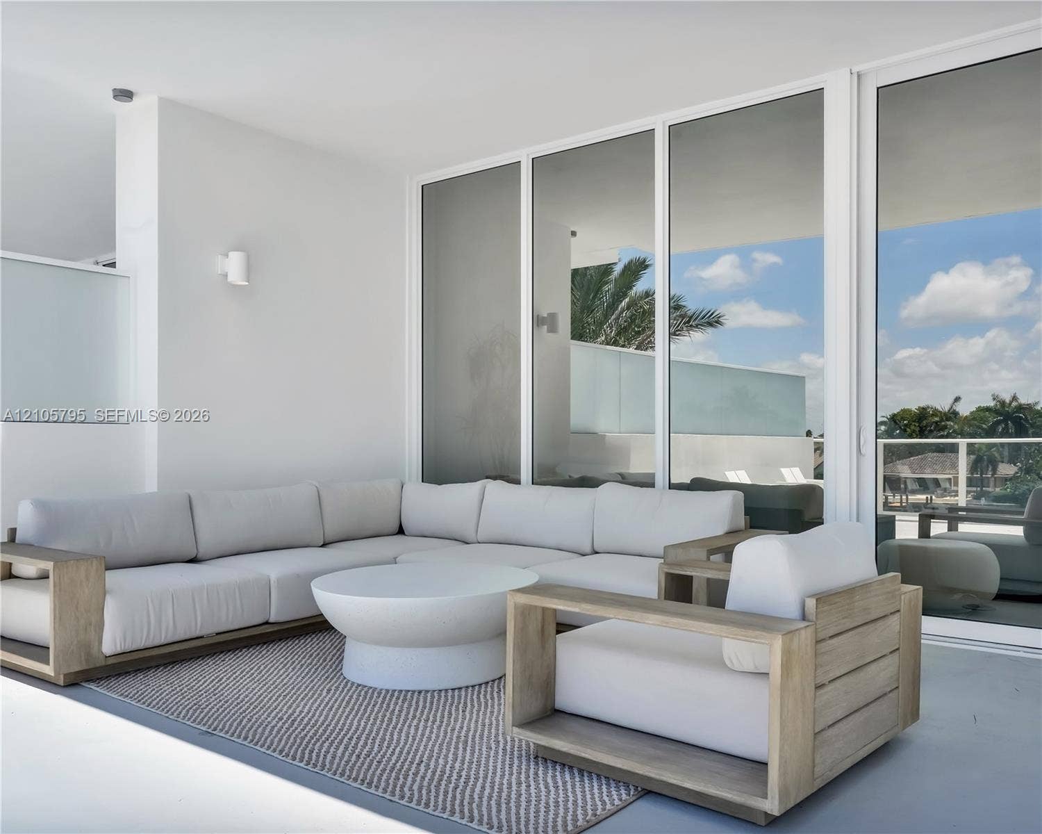 407 N Riverside Drive, #202, Pompano Beach, Pompano Beach, FL 33062 Covered patio featuring white-frame floor-to-ceiling glass sliding doors, smooth concrete flooring, and minimalist wall-mounted light fixtures