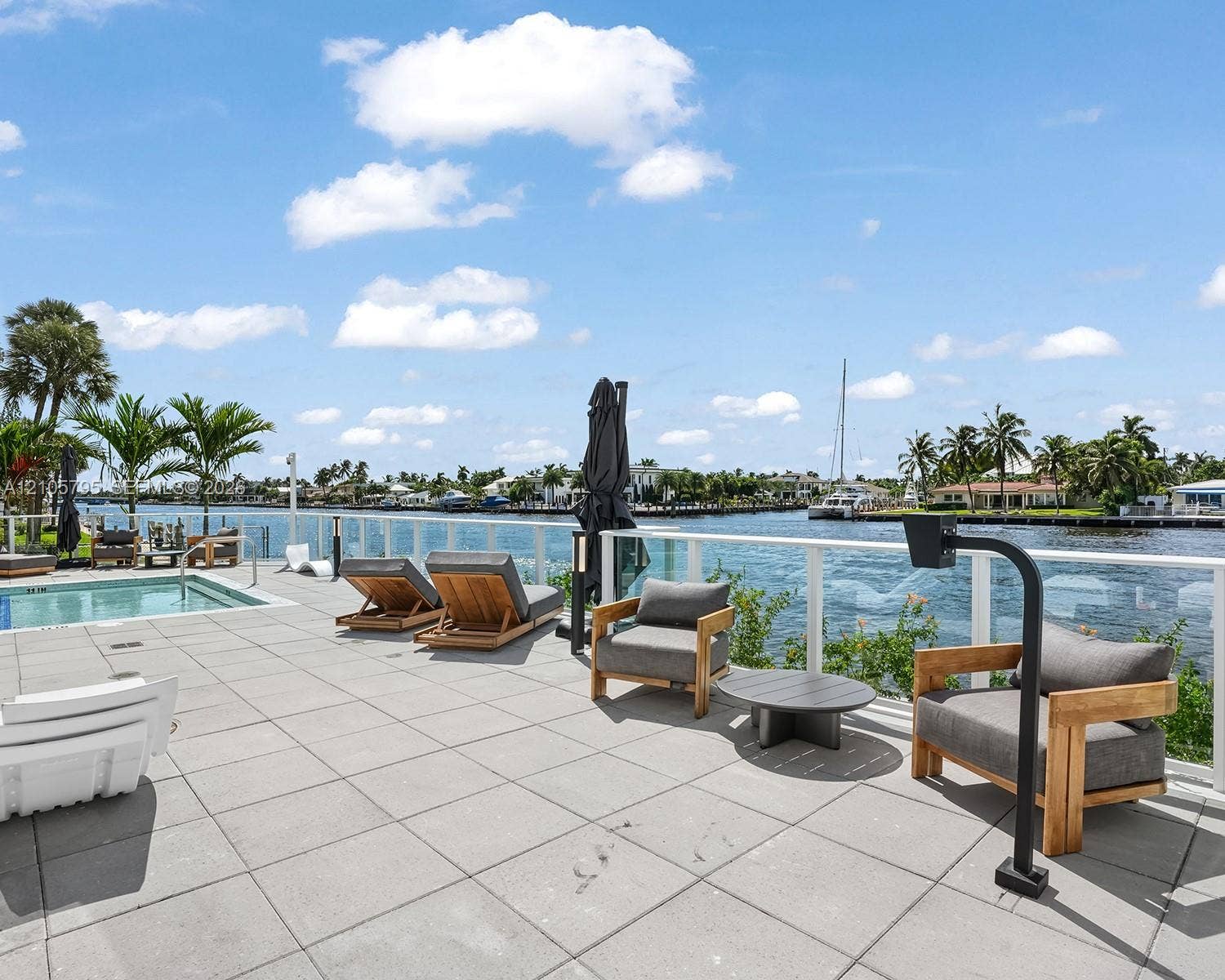 407 N Riverside Drive, #202, Pompano Beach, Pompano Beach, FL 33062 Waterfront terrace featuring a tiled deck, built-in pool, and glass railing system overlooking the canal