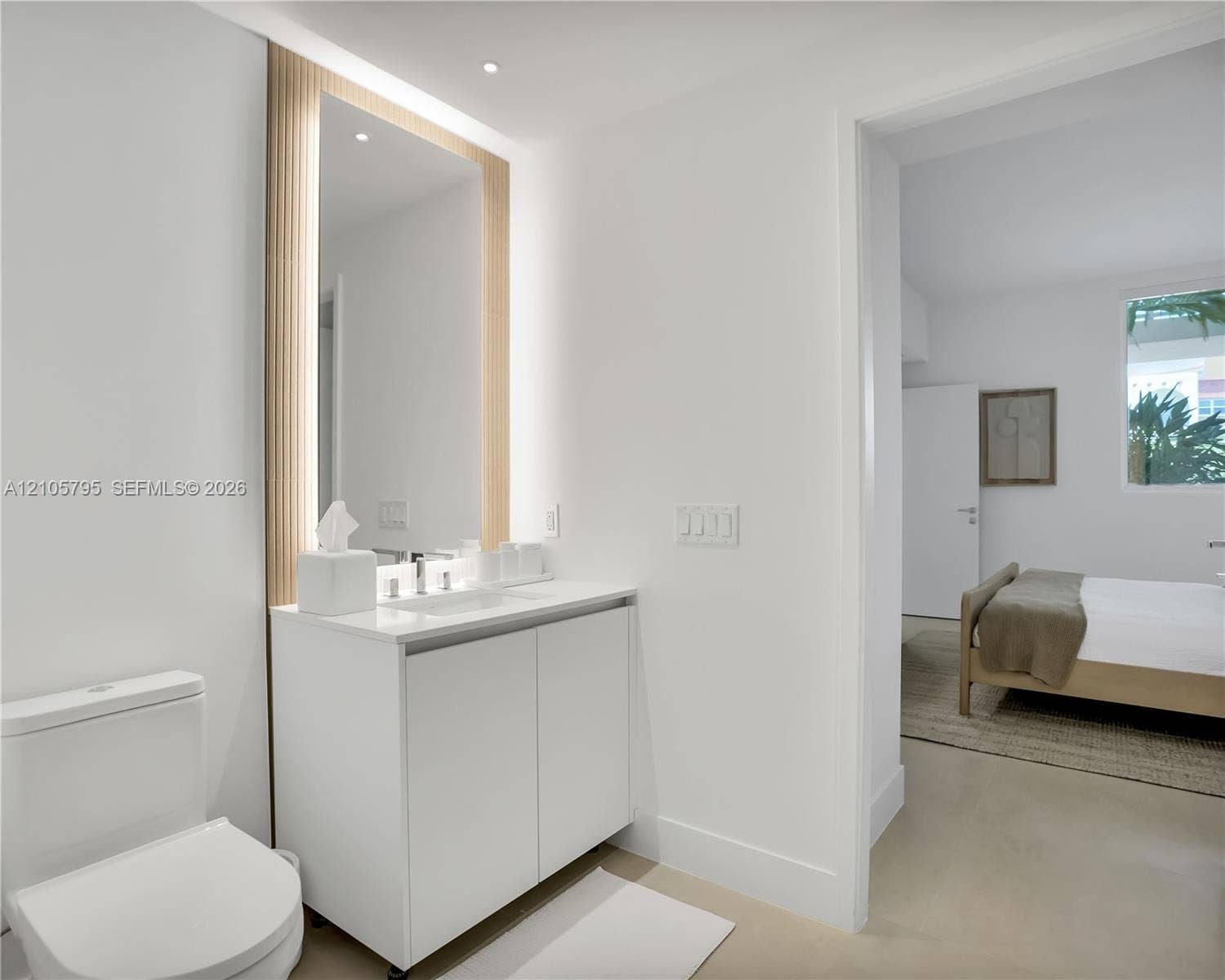 407 N Riverside Drive, #202, Pompano Beach, Pompano Beach, FL 33062 Modern vanity featuring a white cabinet, integrated countertop basin, and polished chrome faucet, accented by a full-height mirror with vertical fluted wood-finish surround and integrated LED lighting