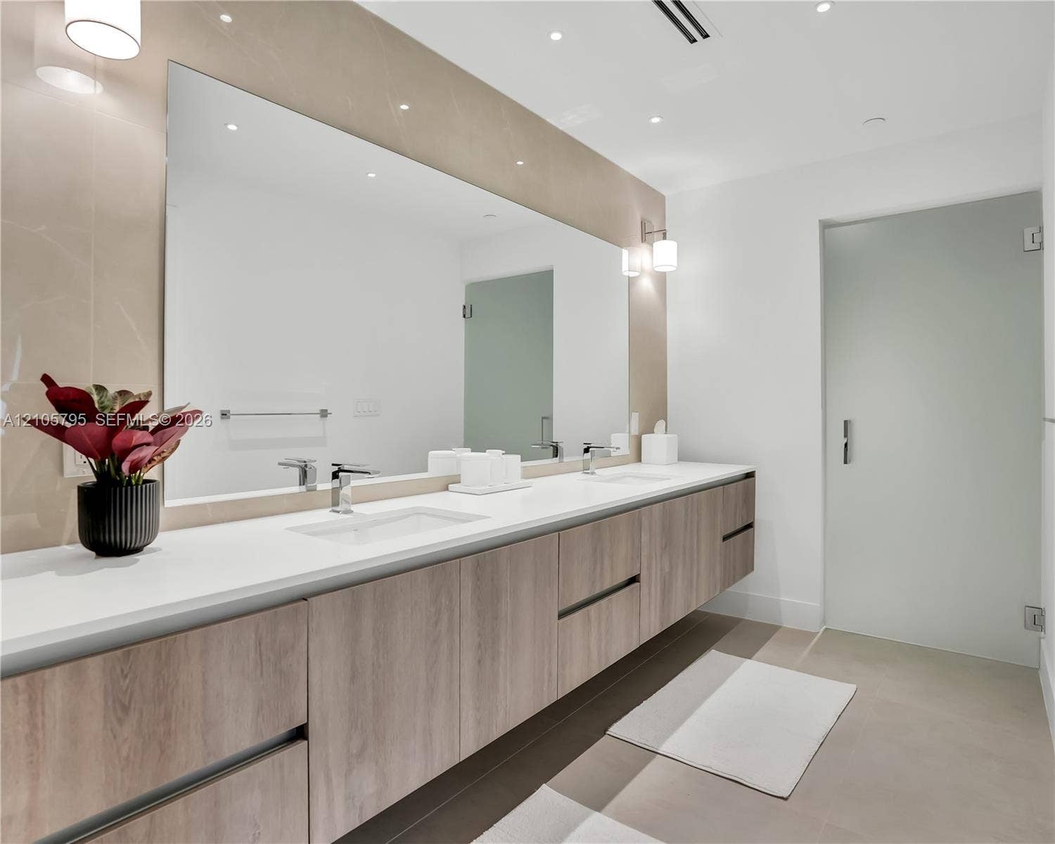 407 N Riverside Drive, #202, Pompano Beach, Pompano Beach, FL 33062 Floating wood-finish vanity with dual integrated rectangular sinks, expansive wall-to-wall mirror, quartz countertop, and frosted glass door