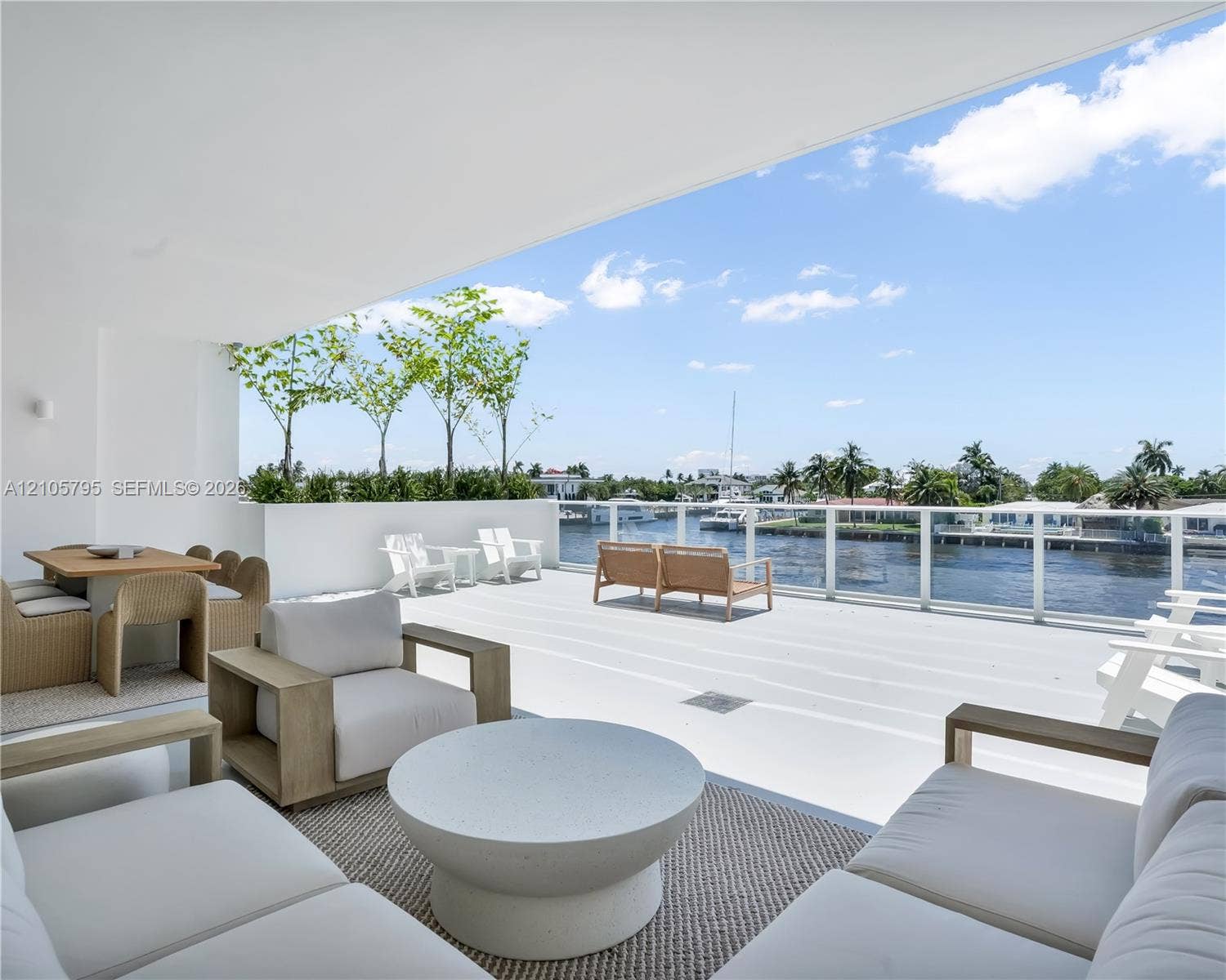 407 N Riverside Drive, #202, Pompano Beach, Pompano Beach, FL 33062 Expansive covered balcony featuring white decking, a minimalist white perimeter wall, and a full-length glass railing overlooking the waterway