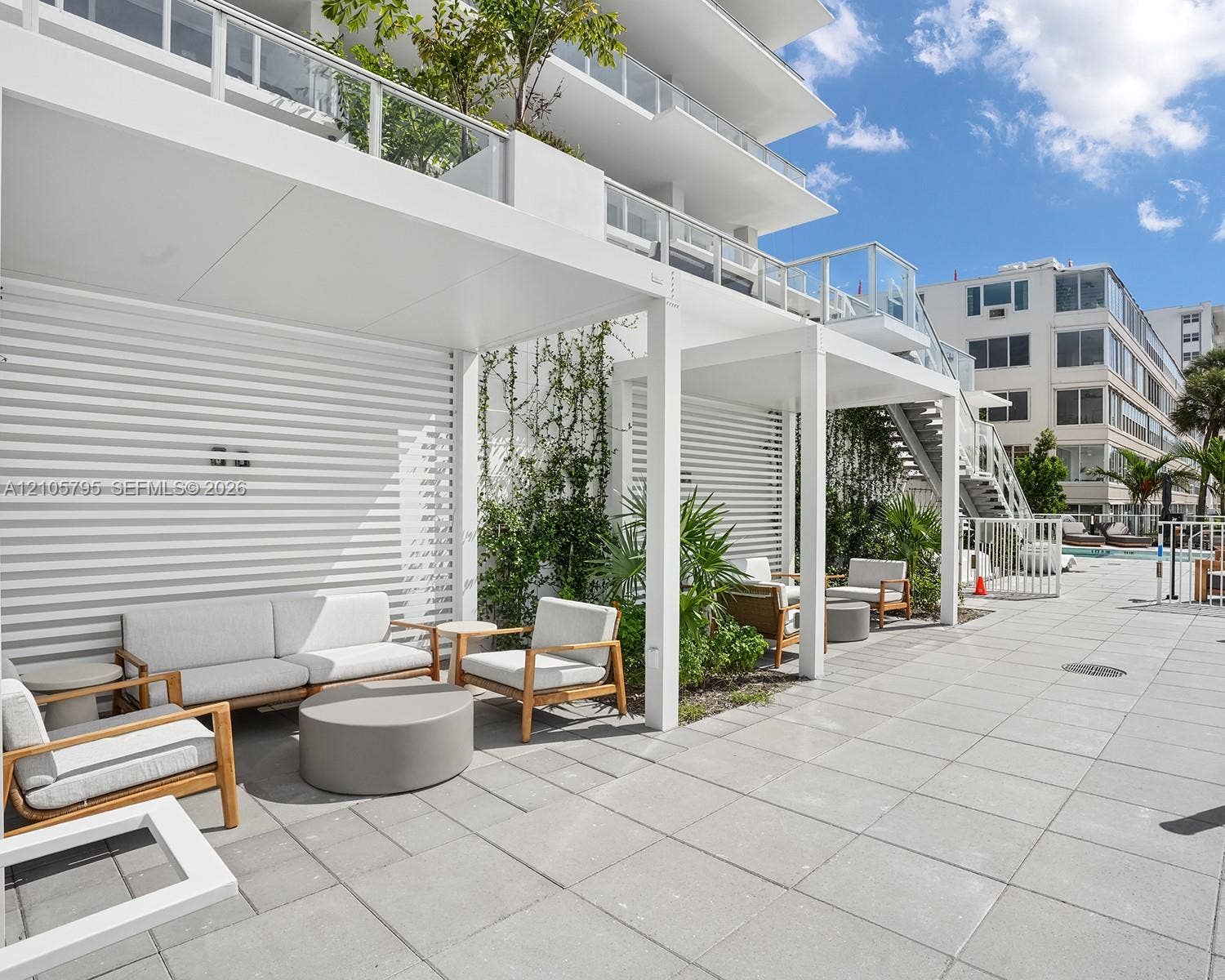407 N Riverside Drive, #202, Pompano Beach, Pompano Beach, FL 33062 Outdoor terrace featuring a concrete paver patio, white aluminum pergolas, horizontal slat privacy walls, and glass-paneled balconies