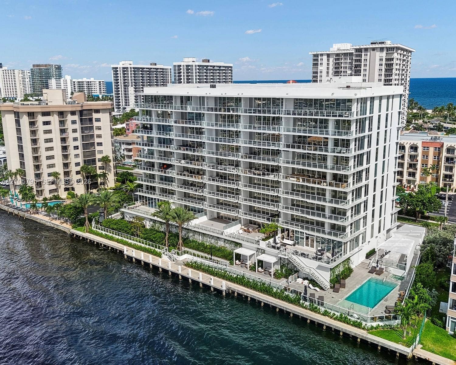 407 N Riverside Drive, #202, Pompano Beach, Pompano Beach, FL 33062 Waterfront mid-rise building featuring extensive private balconies, a ground-level swimming pool, manicured landscaping, and a direct bulkhead seawall