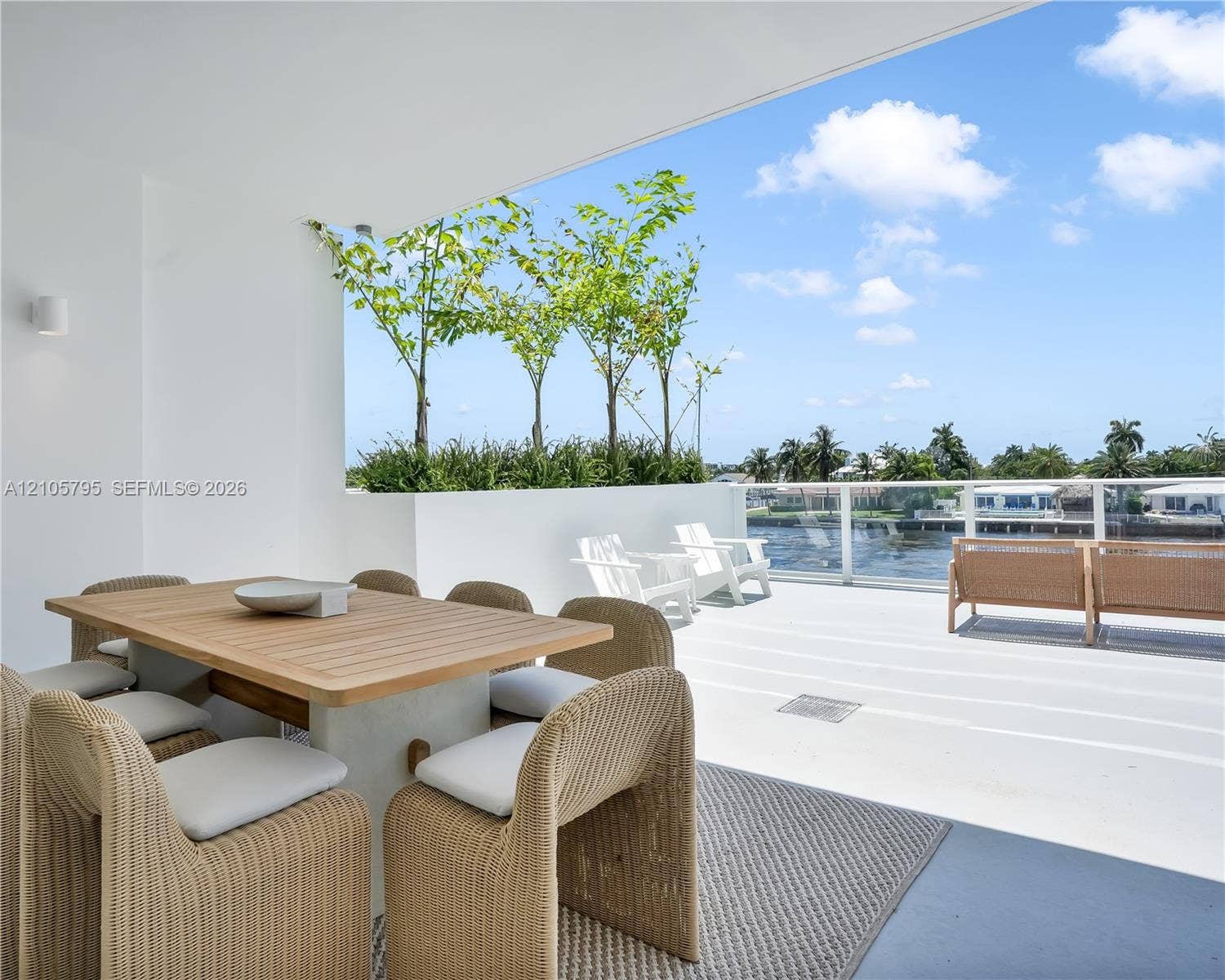 407 N Riverside Drive, #202, Pompano Beach, Pompano Beach, FL 33062 Covered terrace featuring a glass panel railing, built-in planter boxes with mature trees, and smooth concrete flooring
