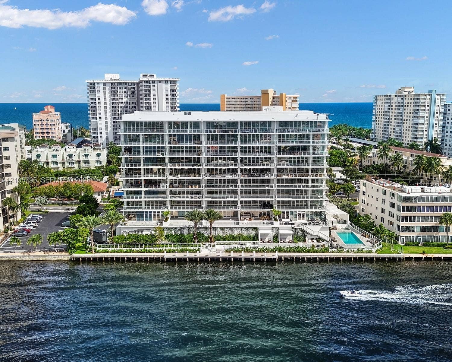 407 N Riverside Drive, #202, Pompano Beach, Pompano Beach, FL 33062 Waterfront multi-story residential building featuring floor-to-ceiling glass balconies, private dockage, a ground-level swimming pool, and manicured landscaping