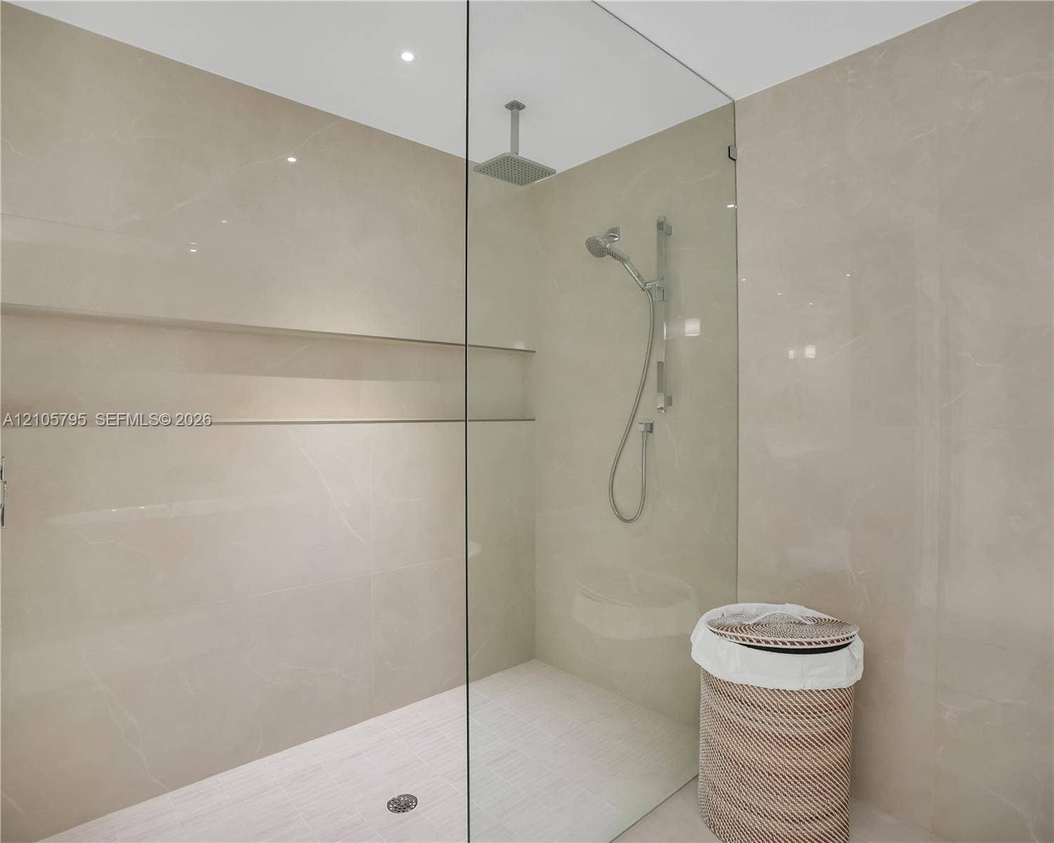 407 N Riverside Drive, #202, Pompano Beach, Pompano Beach, FL 33062 Walk-in shower featuring large-format stone-finish tile surround, integrated recessed shelving, a frameless glass enclosure, a ceiling-mounted rainfall showerhead, and a hand-held shower wand