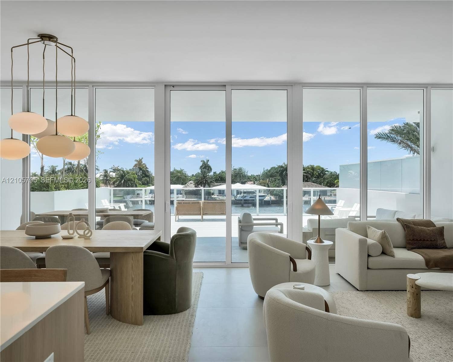 407 N Riverside Drive, #202, Pompano Beach, Pompano Beach, FL 33062 Floor-to-ceiling glass paneling with central sliding doors, expansive balcony, large-format tile flooring, and custom multi-light chandelier fixture