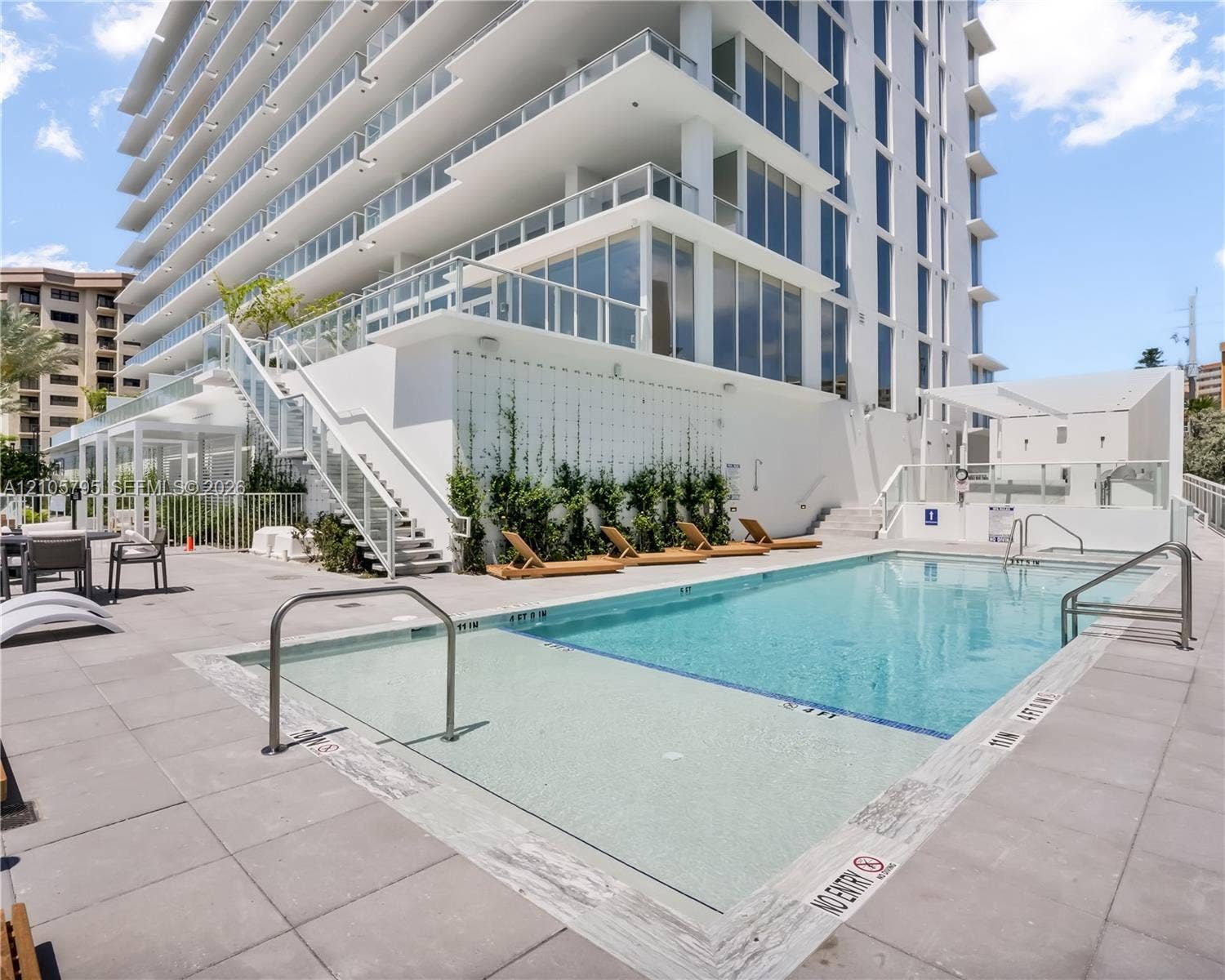 407 N Riverside Drive, #202, Pompano Beach, Pompano Beach, FL 33062 Swimming pool with a baja shelf, expansive concrete deck, metal railings, and exterior wall with integrated climbing vegetation