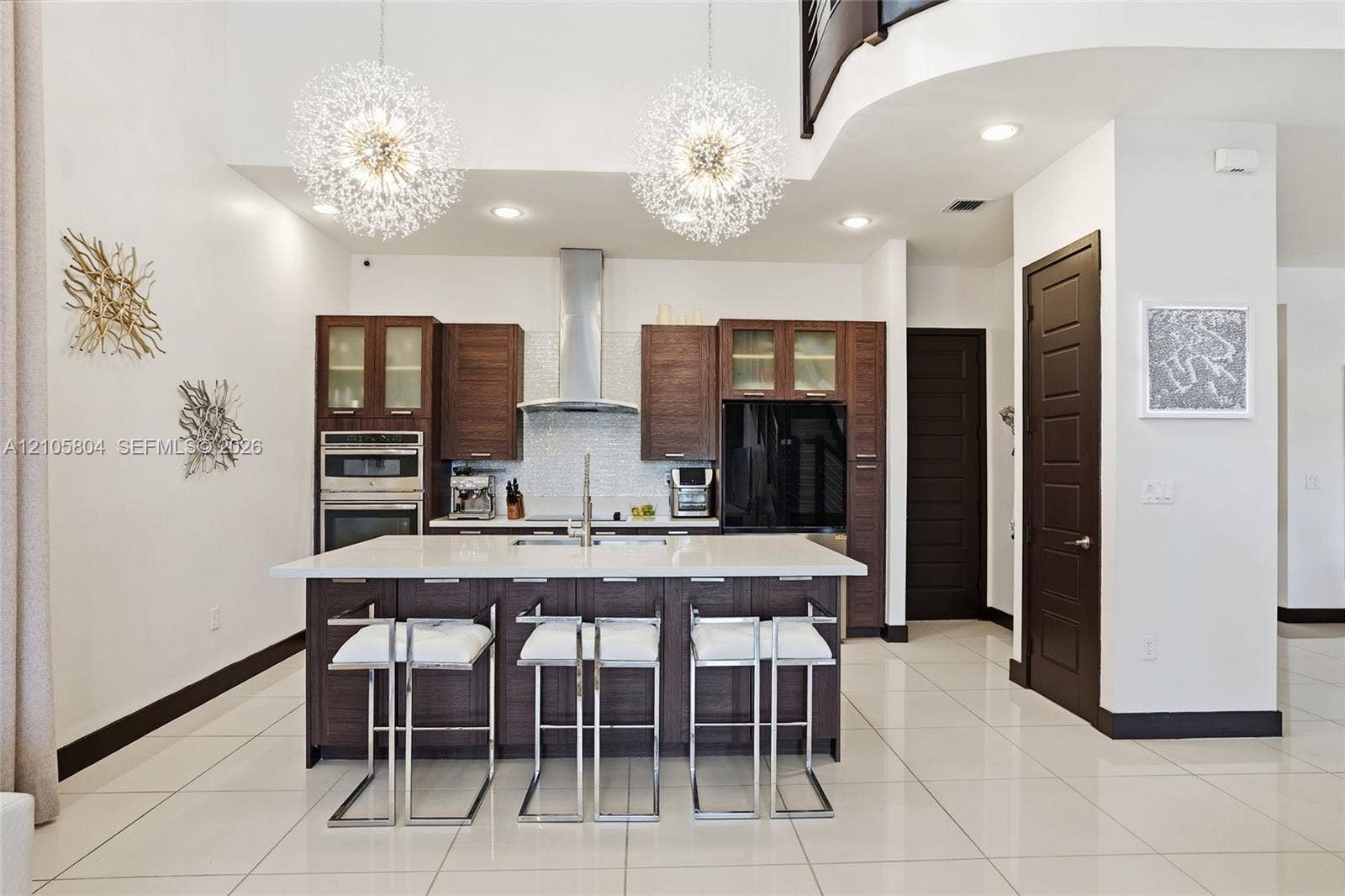 15932 SW 136th Way, Miami, FL 33196 Kitchen featuring dark wood-finish cabinetry, a white stone island countertop, a stainless steel chimney-style range hood, recessed ceiling lighting, and two sphere-shaped pendant light fixtures