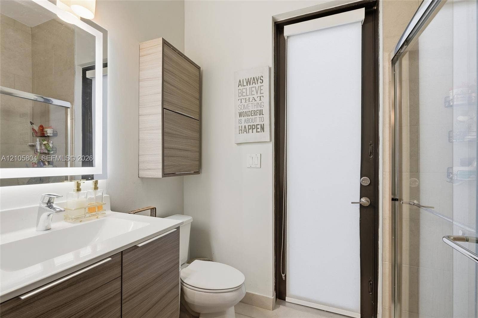 15932 SW 136th Way, Miami, FL 33196 Bathroom featuring a vanity with integrated sink, wood-finish cabinetry, a backlit mirror, a wall-mounted storage cabinet, and a glass-enclosed shower
