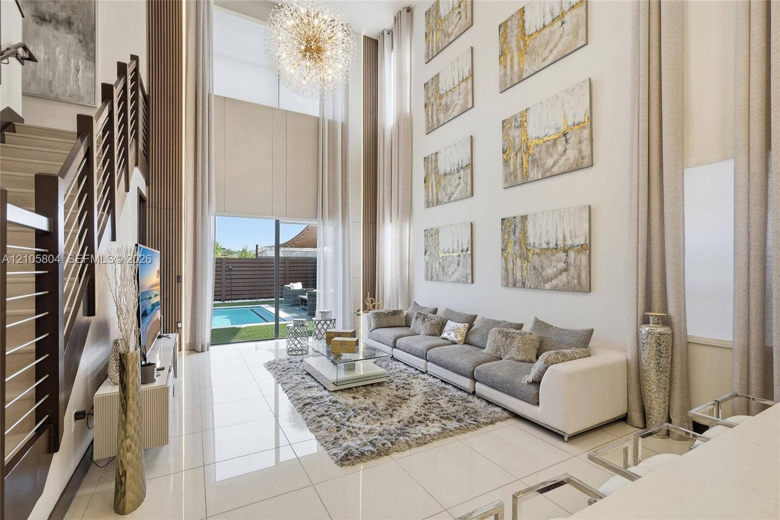 15932 SW 136th Way, Miami, FL 33196 Double-height ceilings featuring floor-to-ceiling windows, polished tile flooring, a statement chandelier, and a staircase with a horizontal cable railing system