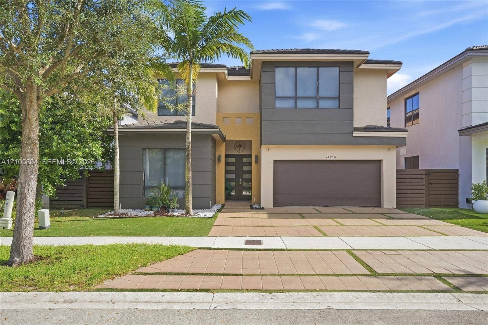 15932 SW 136th Way, Miami, FL 33196 Two-story contemporary exterior featuring a multi-tonal facade, recessed entryway with multi-panel double doors, two-car garage, and geometric paver driveway