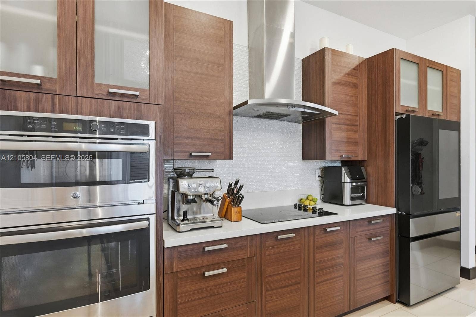 15932 SW 136th Way, Miami, FL 33196 Kitchen featuring wood-finish cabinetry, stone-surface countertops, textured tile backsplash, stainless steel double wall ovens, and a stainless steel range hood