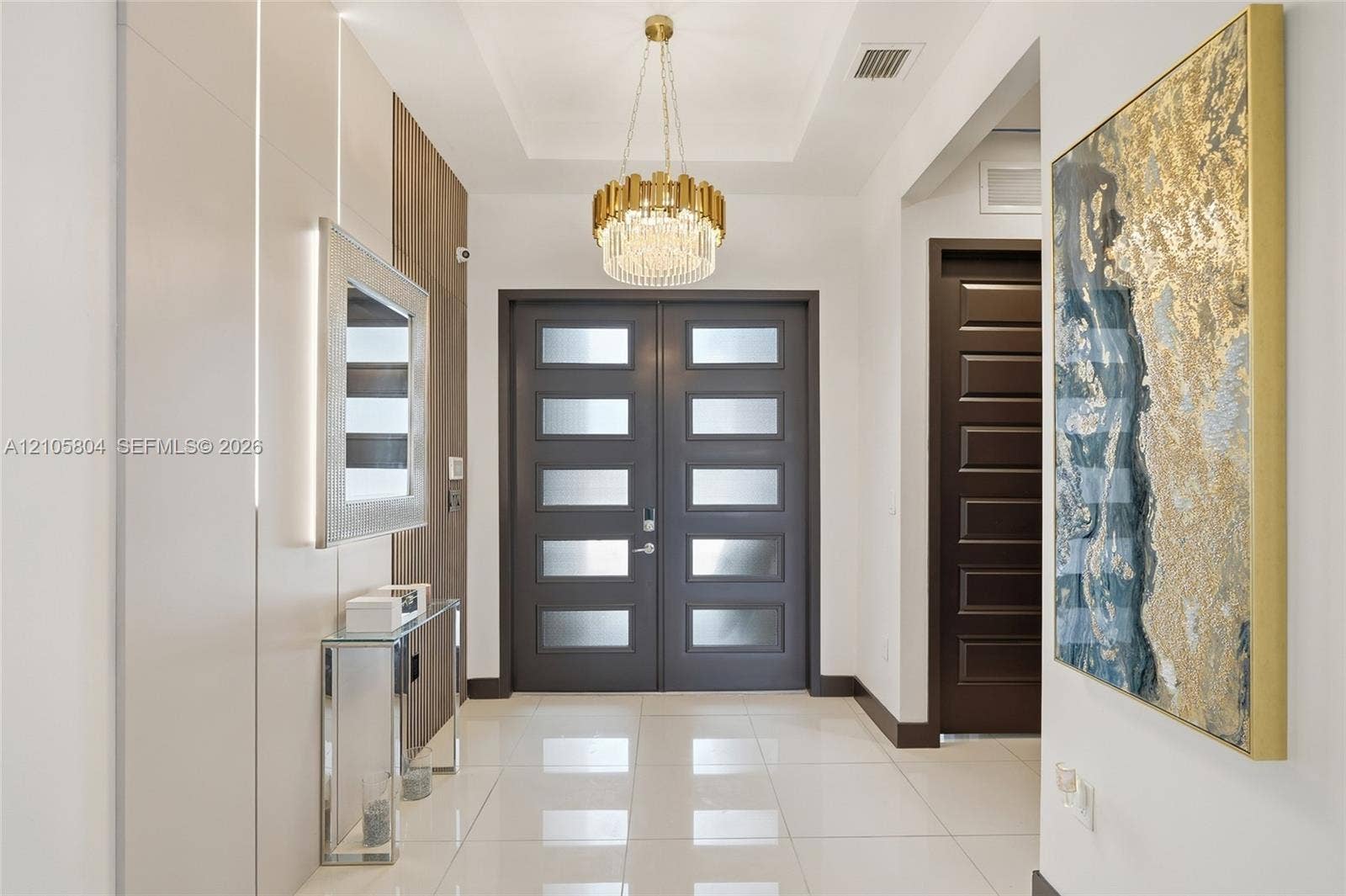 15932 SW 136th Way, Miami, FL 33196 Entryway featuring a double-door entrance with frosted glass panels, tile flooring, a tiered crystal chandelier, and integrated wall paneling with recessed lighting