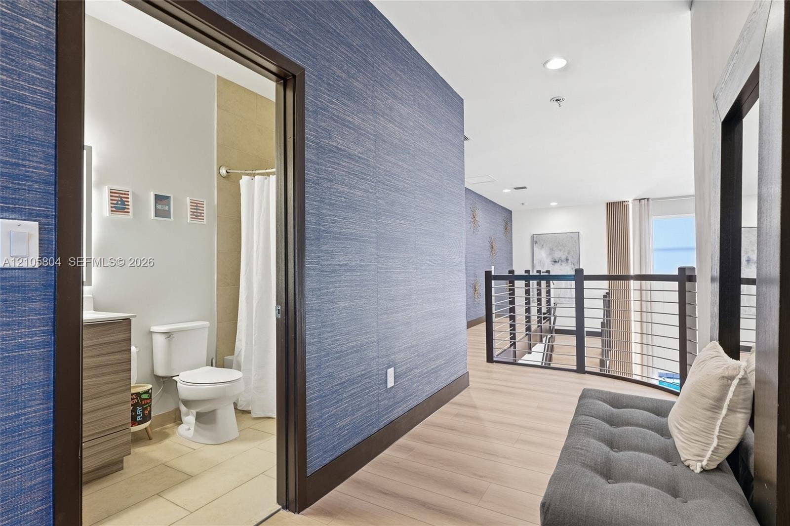 15932 SW 136th Way, Miami, FL 33196 Textured blue wall covering, wood-finish flooring, metal railing with horizontal bars, and bathroom featuring a vanity with integrated sink