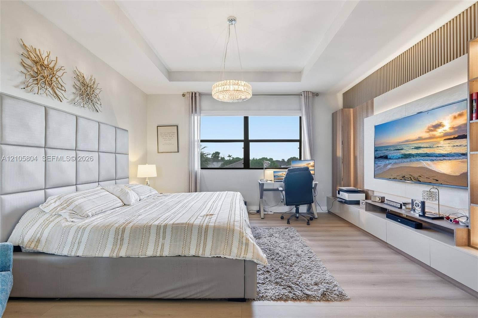 15932 SW 136th Way, Miami, FL 33196 Tray ceiling, custom wood-slat wall feature, built-in media cabinetry, crystal chandelier, and wood-finish flooring