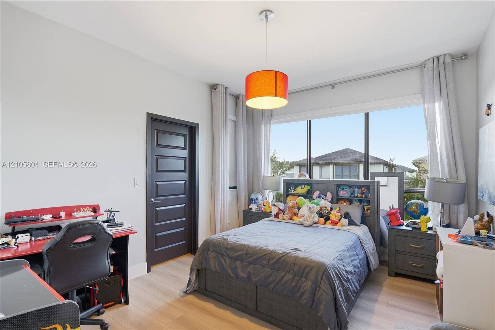 15932 SW 136th Way, Miami, FL 33196 Room featuring wood-finish flooring, a large multi-pane window, and a dark-finished five-panel interior door with a brushed-metal lever handle